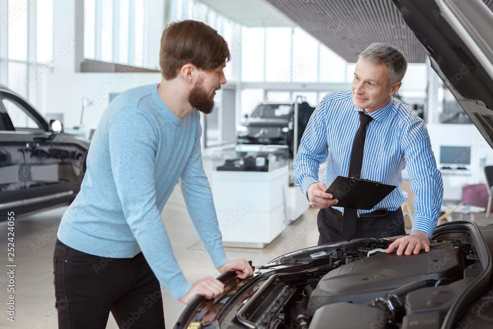 Handsome young man buying car from a professional dealer Handsome young man buying car from a professional dealer