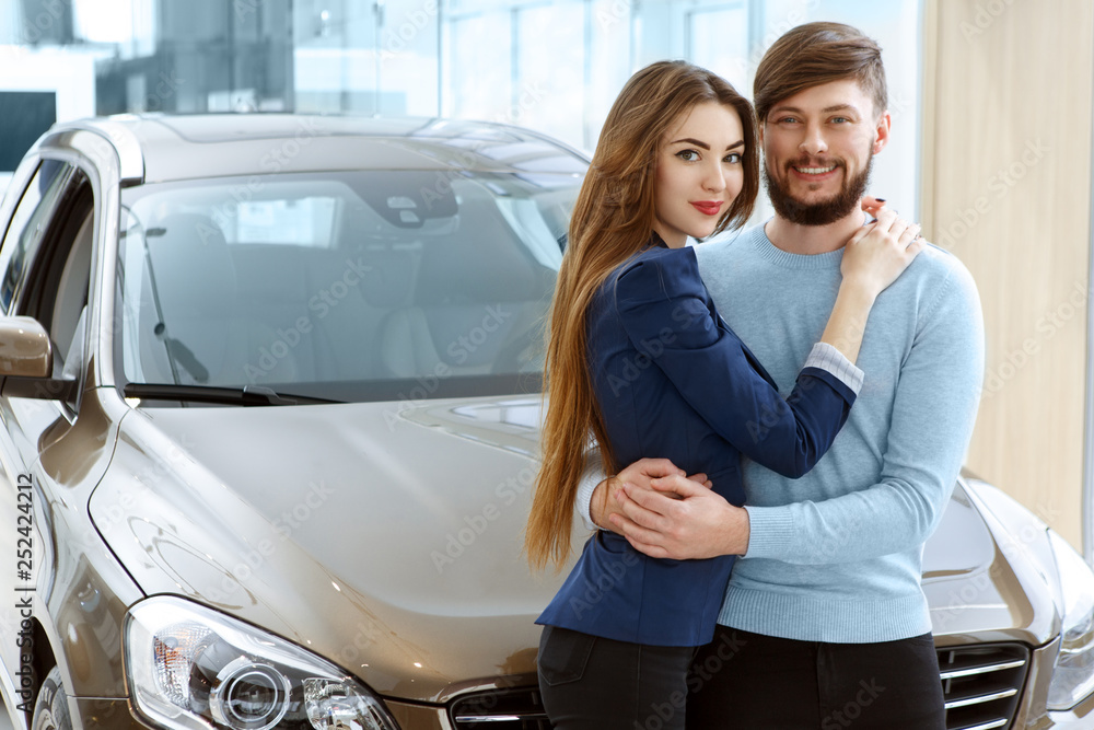 Φωτογραφία Beautiful happy couple buying a new car at the car dealership center