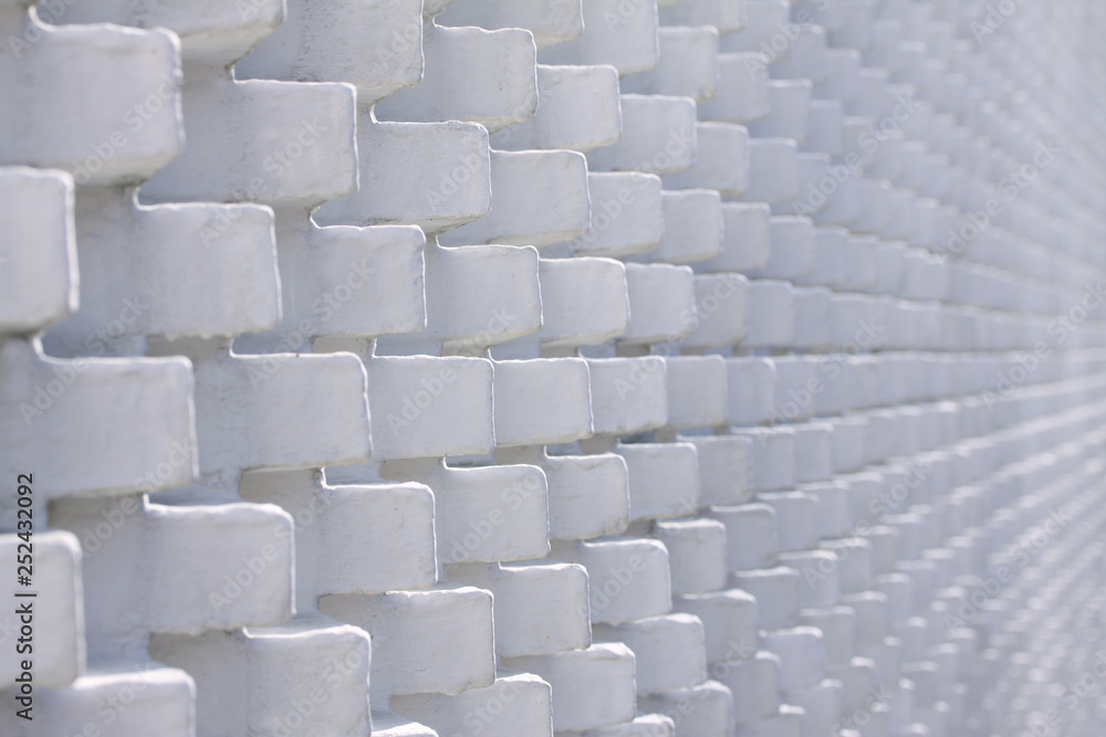 Fototapeta premium White brick wall in unusual pattern with bricks sticking out - selective focus