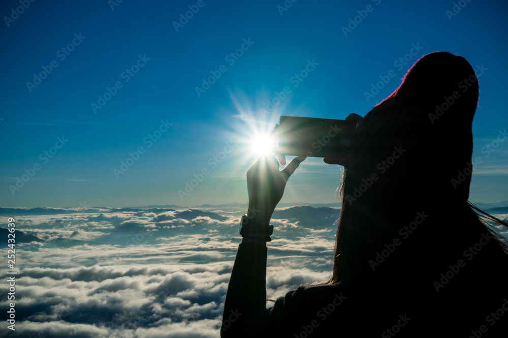 tourist girl taking photo sunrise and sea of fog view on phu chi fa mountain area and national forest park in chiang rai, Thailand.
