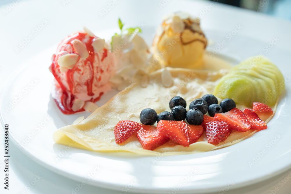Fruity Crepe Ice Cream with scoops of vanilla and strawberry on white plate. Fruity Crepe Ice Cream with scoops of vanilla and strawberry on white plate.