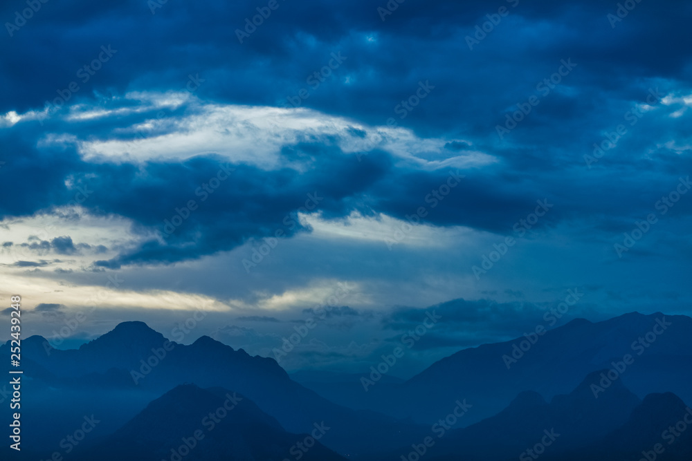 Beautiful sunset sky over peaks of mountains. Horizontal color photography.