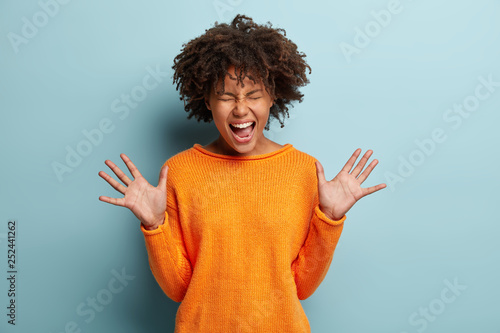 Fotografija Emotional overjoyed woman raises hands, shows palms, feels great pleasure, excla