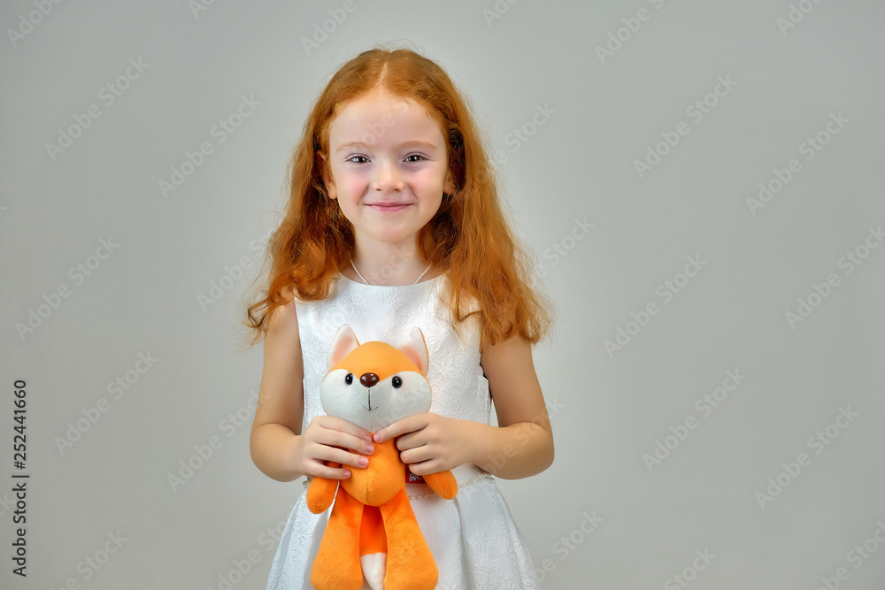 Concept portrait of a cute pretty child girl with red hair on a gray background smiling and talking Concept portrait of a cute pretty child girl with red hair on a gray background smiling and talking
