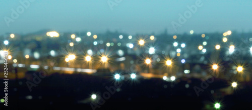 Defocused or blurred image of multi-colored lights in the city streets. Abstract background, selective focus. Banner