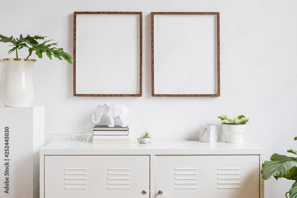 Stylish scandi home interior with two brown wooden mock up photo frames  with books, beautiful plants in vase, elephant figure and home accessories.  Minimalistic concept of white room decor. Stock-Foto | Adobe