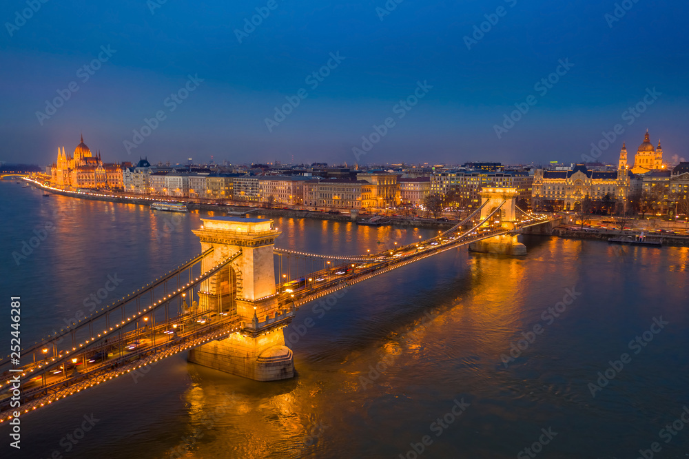 Fototapeta premium Budapest, Hungary - Aerial view of the famous illuminated Szechenyi Chain Bridge at blue hour with Parliament building and St.Stephen's Basilica at the background