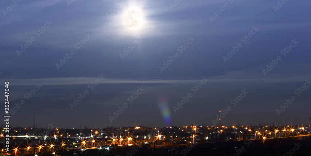 Multi-colored lights on the streets of the city. Full moon, blurred image. Abstract background, selective focus. Banner