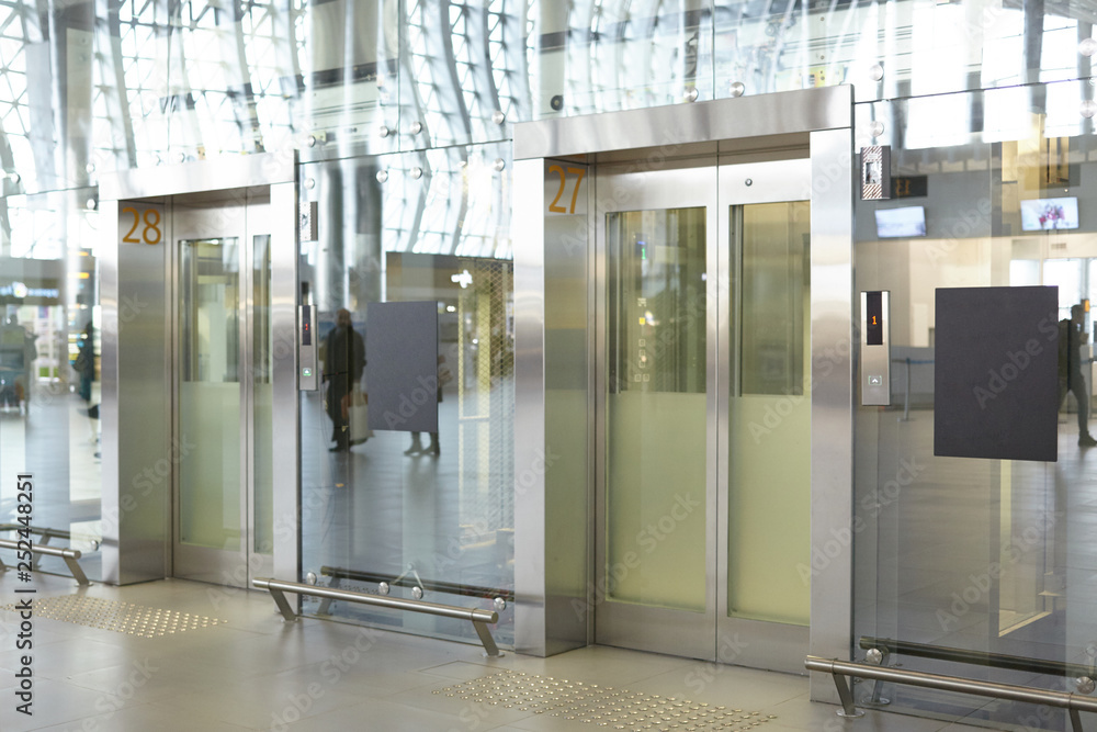 Two clean neat elevator in modern airport terminal or railway depot station with glass walls and metal doors. High speed lifts in shopping mall. Technology, lifestyle, construction and transportation Two clean neat elevator in modern airport terminal or railway depot station with glass walls and metal doors. High speed lifts in shopping mall. Technology, lifestyle, construction and transportation