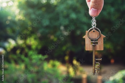 Hanging home key with house keyring with green garden background © sundaemorning