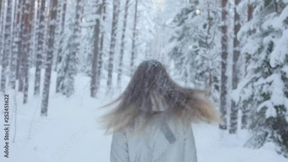 Stylish young beautiful woman walking outdoors in winter park on a snowy background. looking at the camera. It is snowing, a beautiful young woman walking in a winter park understands her hands. Stylish young beautiful woman walking outdoors in winter park on a snowy background. looking at the camera. It is snowing, a beautiful young woman walking in a winter park understands her hands.