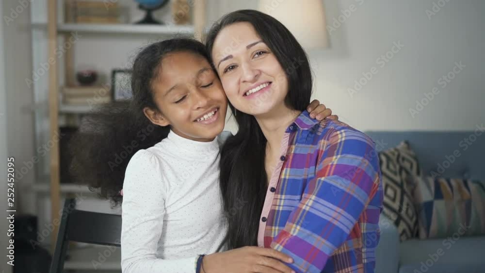Portrait of african american young girl talking and laughing with her adult school teacher looking in camera. Front view of Informal communication of tutor and black girl in primary school in Portrait of african american young girl talking and laughing with her adult school teacher looking in camera. Front view of Informal communication of tutor and black girl in primary school in