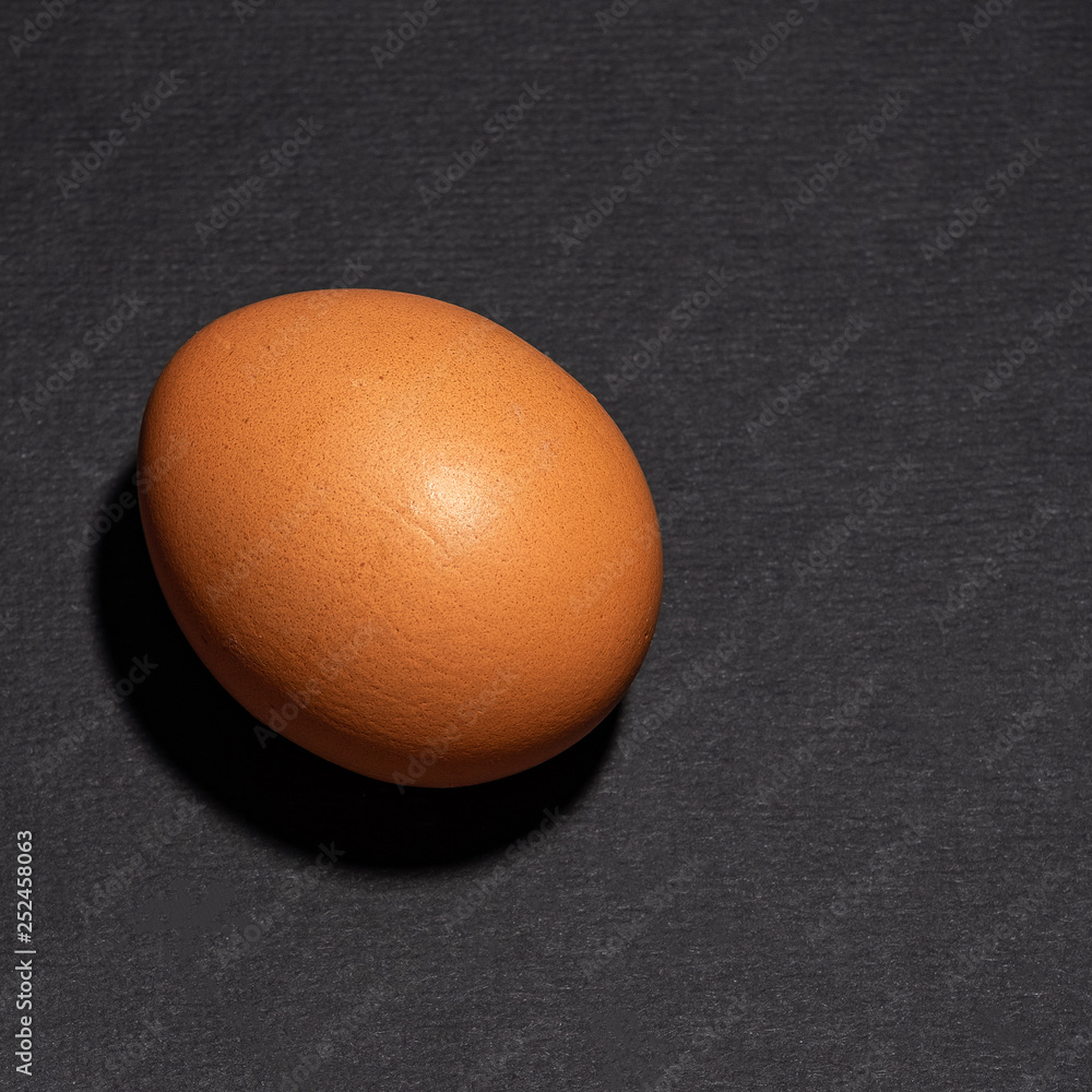chicken egg with brown shell on black background chicken egg with brown shell on black background