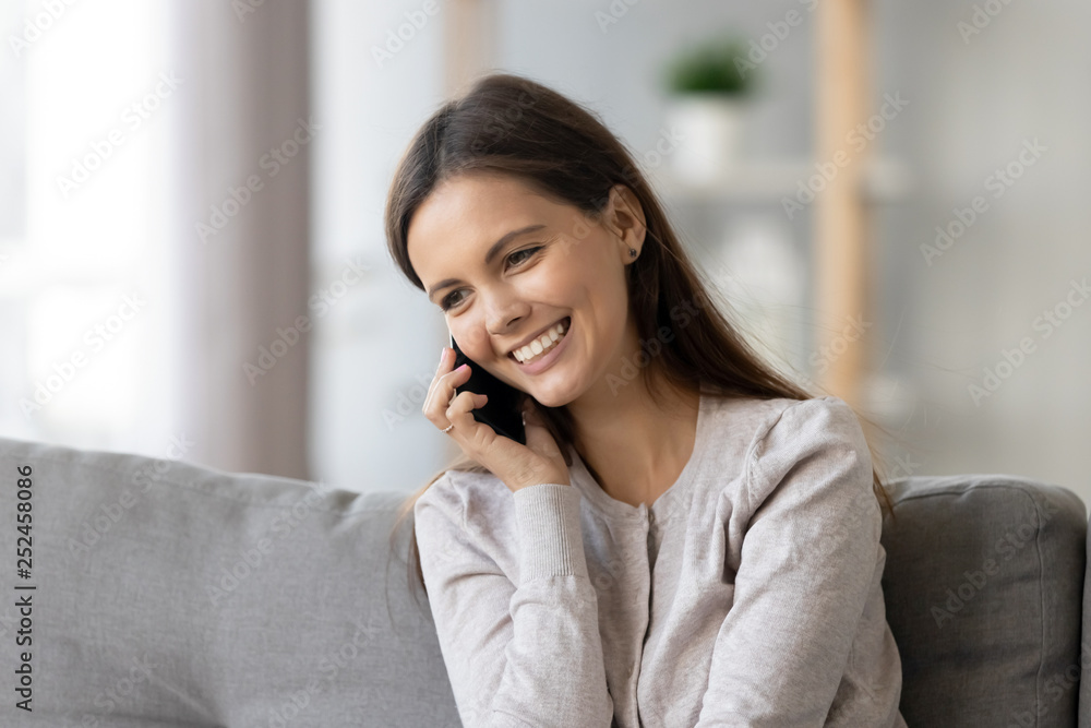 Smiling young woman talking on phone, sitting on sofa at home Smiling young woman talking on phone, sitting on sofa at home