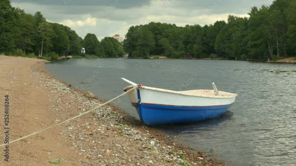 Moored Rowing boat with oars on the river bank Moored Rowing boat with oars on the river bank