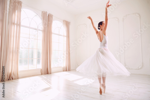 Young ballerina dancing in a white studio