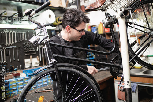 Mechanic repairing a mountain bike in a workshop.