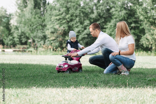parents play with their little son on the lawn in the Park.