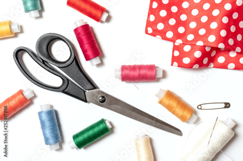 Colored thread coils, scissors, pin and fabric on white background, sewing, handmade and DIY concept - design for seamstress and tailor