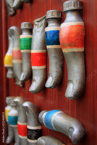 Closeup of paint tubes in the shape of fingers on the red wall, unusual paints. Unique items, equipment for painting.