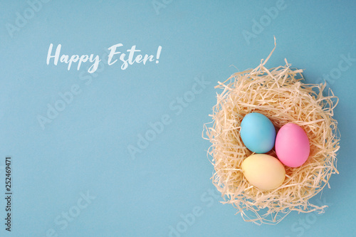 Happy Easter greeting card; Colored eggs in a hen nest.