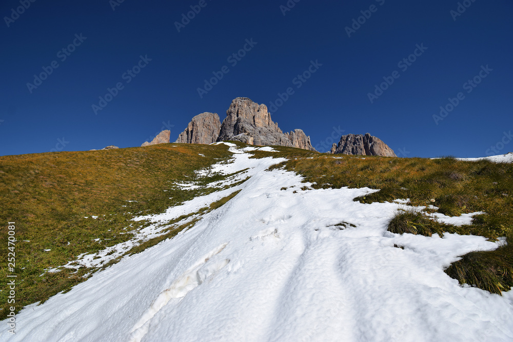 Beautiful view of the italian Alps (Trentino, Italy) during a cold winter/spring morning. The snow is melting because of the spring thaw. Snow and grass in the wilderness.