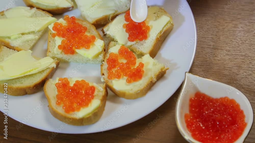 A woman smears red caviar with a spoon of canapes with butter A woman smears red caviar with a spoon of canapes with butter