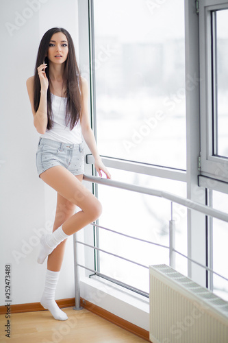 Woman in shorts at window in morning