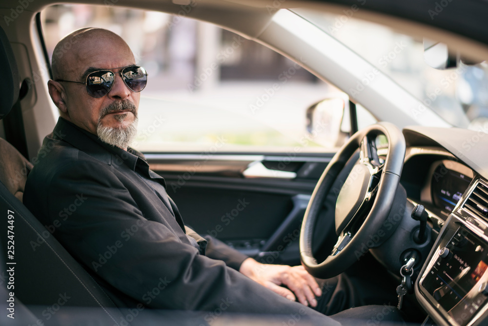 Senior 60s man driving suv luxury car in close up image