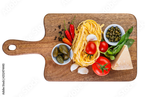 Parmesan, capers, tomato, garlic, basil, chili paprika, pepper and tagliatelle pasta on wooden cutting board isolated on white background. Ingredients for healthy italian lunch or dinner