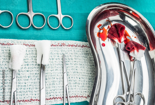 Scissors surgical with torundas soaked with blood on a tray metal in an operating theater, composition horizontal, conceptual image photo