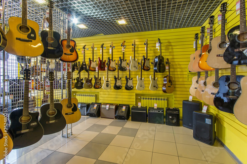 Rows of guitars, both acoustic and electric in a modern musical shop