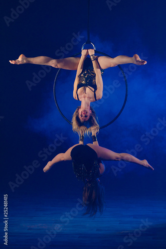 Duet gymnasts girls aerial acrobatics on the ring on the background of blue smoke photo