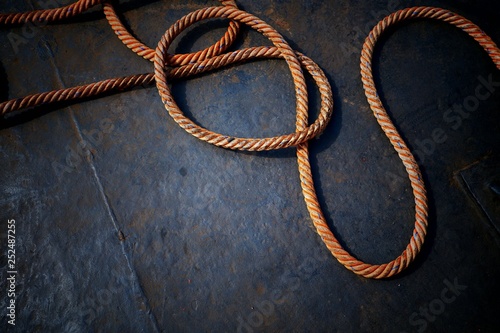 High angle view of the old giant fiber naytical rope on steel boat floor background in dark tone style photo