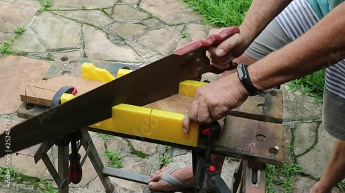 Corte com caixa de esquadria, fazendo corte com um serrote manual usando uma bancada photo