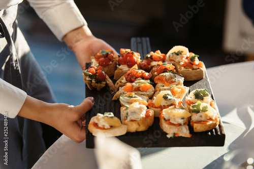 A waiter with a tray of snacks at a banquet or reception. Catering buffet at party