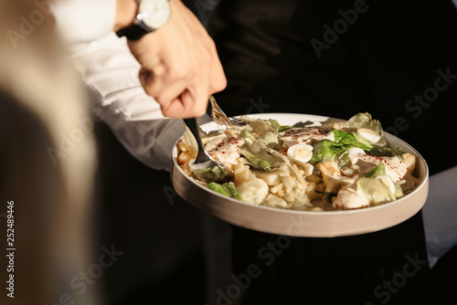 A waiter with a tray of snacks at a banquet or reception. Catering buffet at party