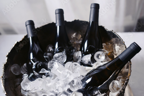Closeup and selective focus of wine and champagne bottles chilling in a bucket full of ice.