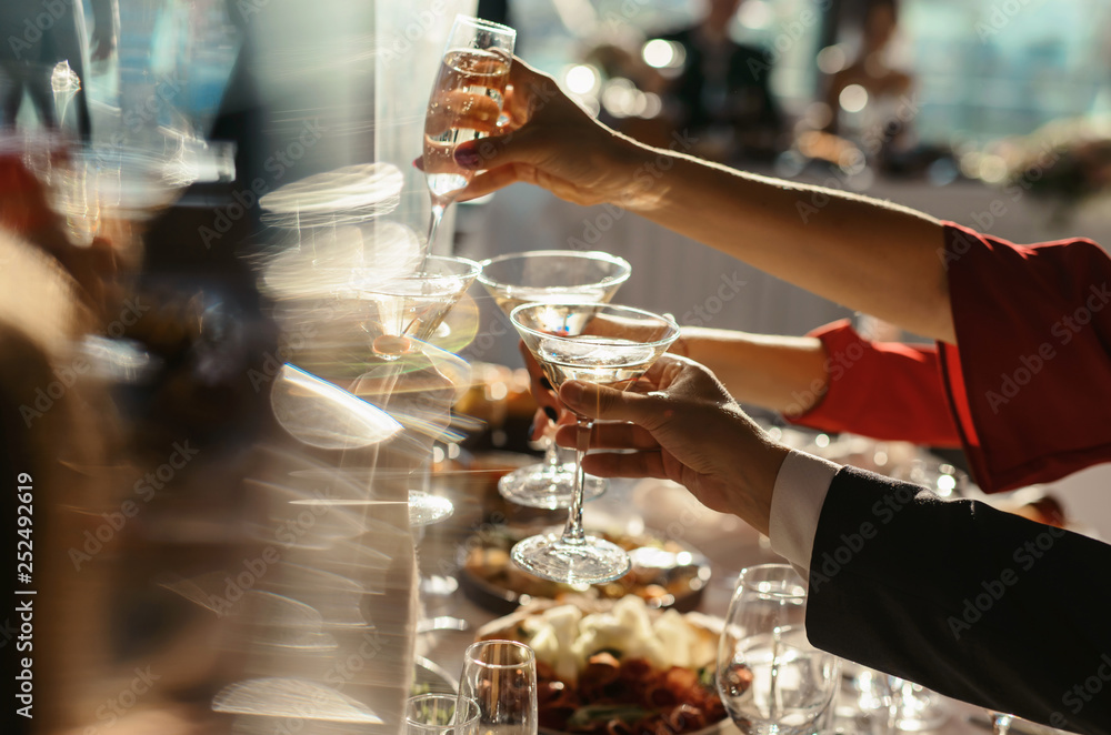 Close up shot of group of people clinking glasses with wine or champagne in front of bokeh background