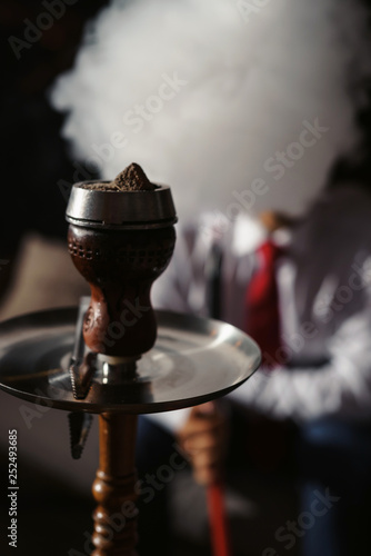 Clay shisha bowl with craft flawoured tobacco and red hot coconut coil with hookah smoke black background isolated. Smoking hookah at party concept photo