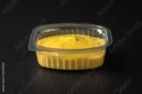 Sauce topping in plastic package for take away or food delivery isolated on a black background.