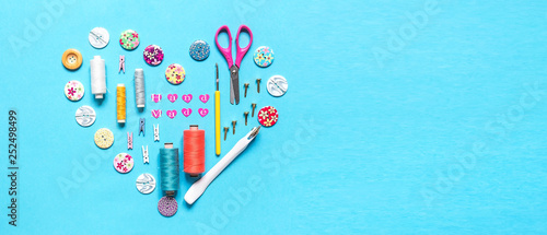 sewing thread set of sewing supplies in knolling pattern on light blue background flat lay top view, template mockup hand made long banner photo