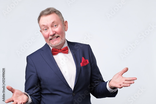 Senior man in blue suit duscussing question with you with open hands gesture photo