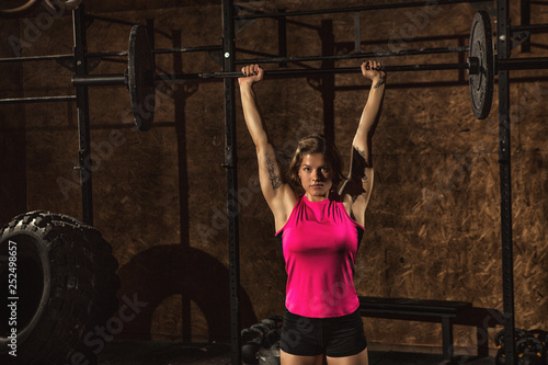 Attractive young female athlete working out with a barbell