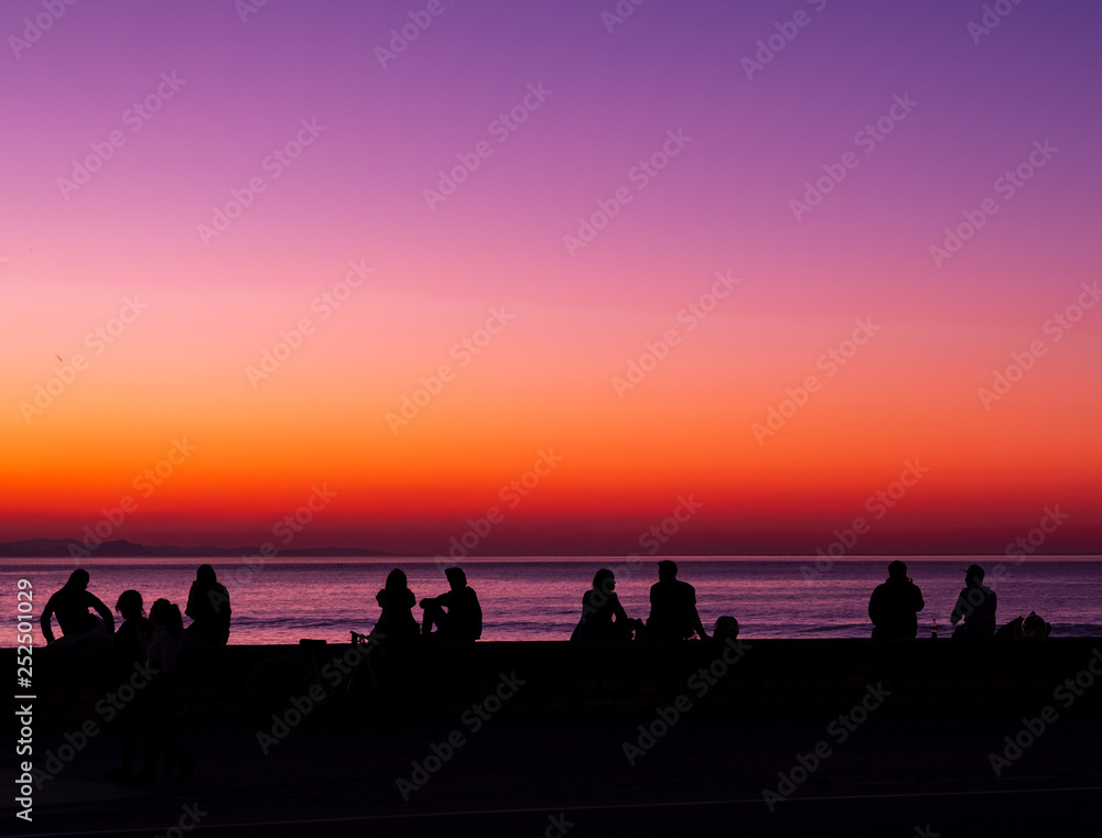 SAN SEBASTIAN, SPAIN - March 02, 2019: People in backlight at the sea at sunset, city of San Sebastian