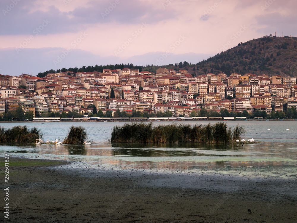 Lake Orestiada and Kastoria city at sunset time, under cloudy sky.