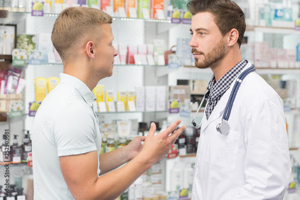 Pharmacist helping his male customer Pharmacist helping his male customer