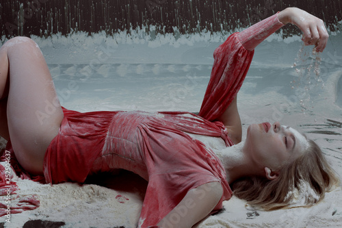 Young woman in a red dress lies in flour.