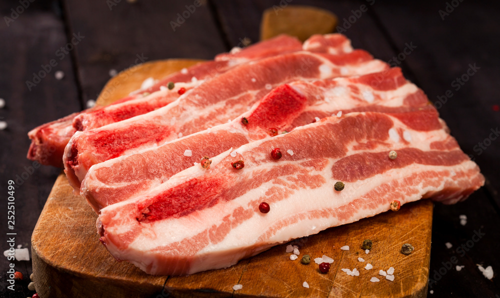 Raw pork steak on a cutting board with spices.