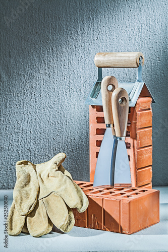 vertical version gloves bricks and trowels on concrette background photo